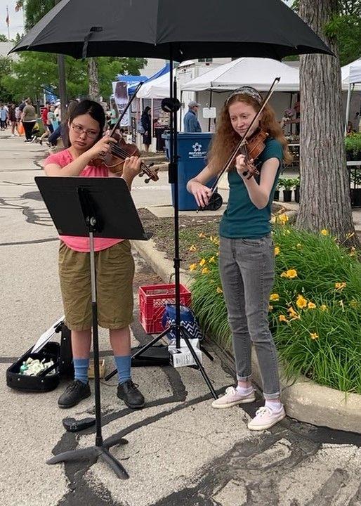 Lauren and Anna playing music outdoors at the local market.